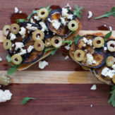 GRILLED EGGPLANT TARTINES WITH ARUGULA, FETA, GREEN OLIVES AND HONEY